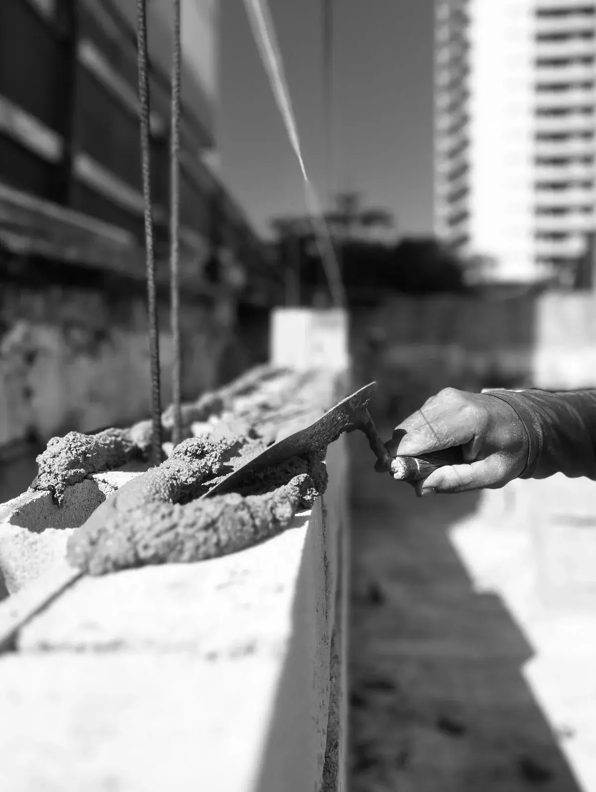 A mason levelling mortar along a blockwork course with a trowel